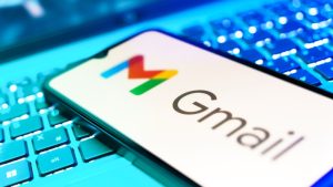 A smartphone with the Gmail logo on it resting on top of a computer keyboard.