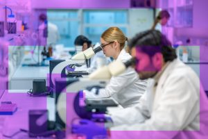 A row of students look down microscopes while sat at a bench in a lab, with a translucent purple geometric graphic overlay adding a technology-focused design element