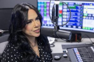 Geraldine "GeeGee" Guzman hosts a radio show on José 97.5 FM while looking at a computer screen